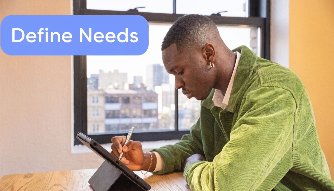 A young man with a gold earring writing on a tablet near a window in an office.