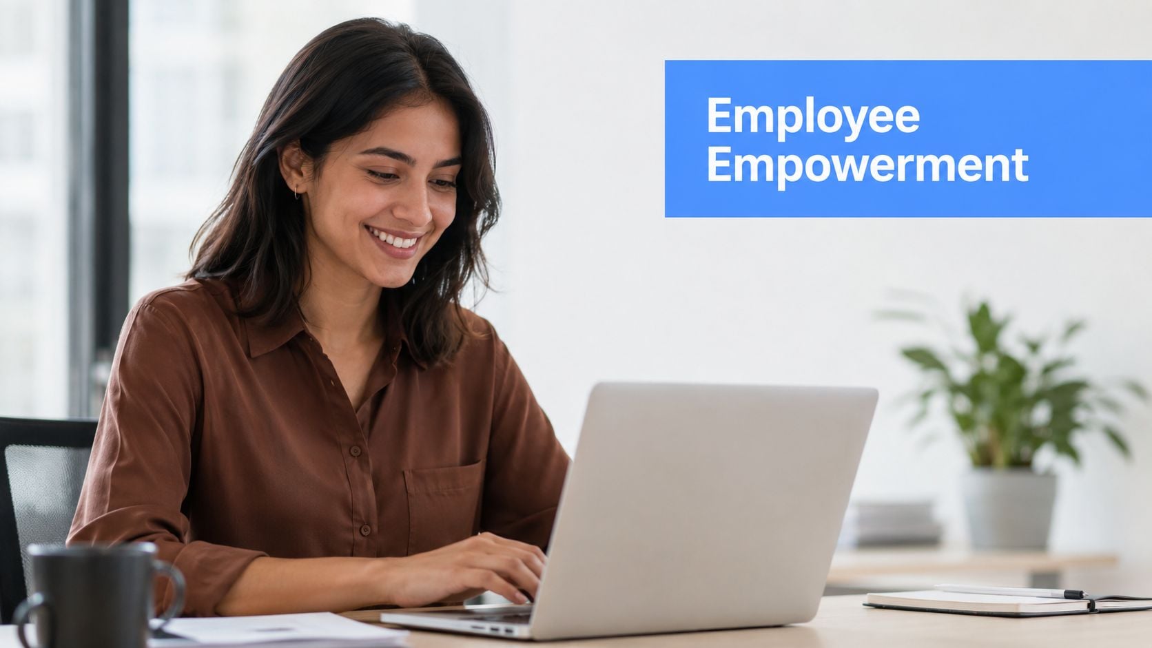 A professional woman smiling while working on her laptop in a bright office environment.